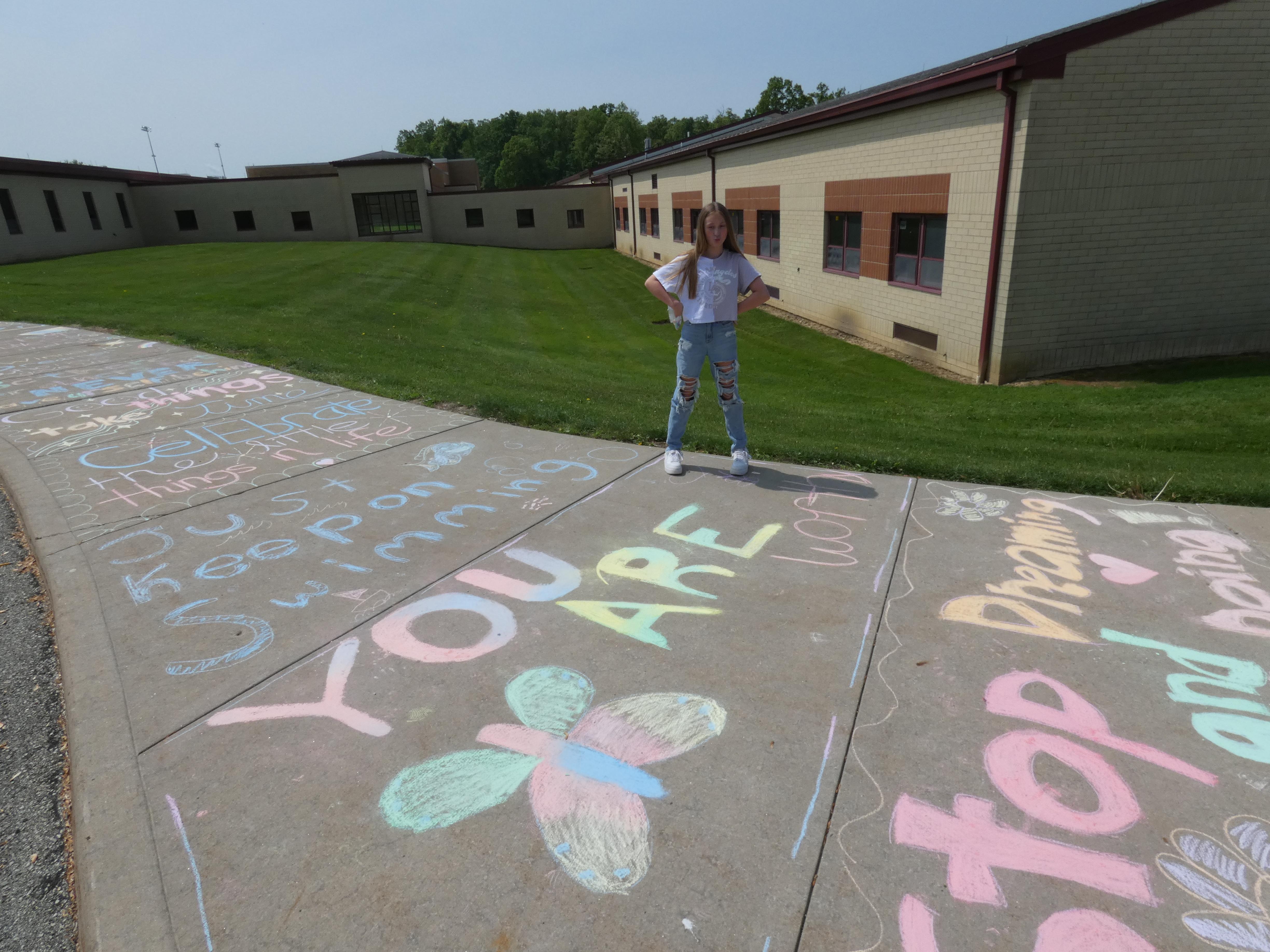 pic of student standing next to a message written in chalk